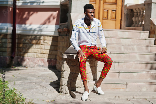 Portrait of handsome stylish african american model man in red throusers and white shirt. photo