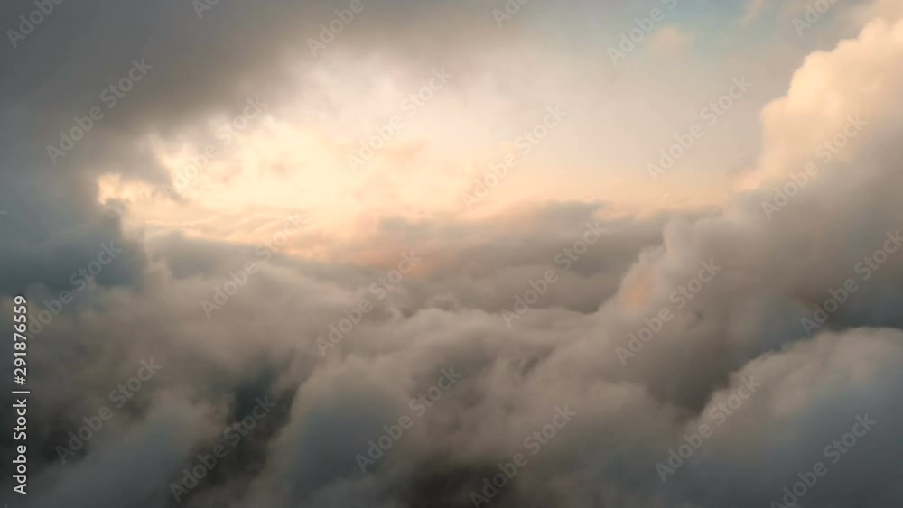 Aerial view flying through cumulus thunderclouds at sunset. Gold colored sunset cloudiness in high contrast. Real sky. The concept of dreams and weather forecast
