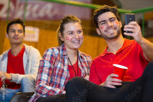 couple taking selfie in the stands during sports match photo