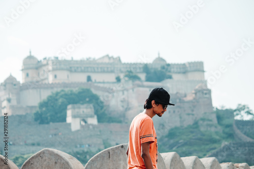 Indian male model wearing hat and sunglasses standing in front of the Kumbhalgarh Fort in Udaipur, Rajasthan, India