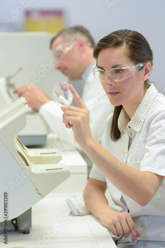 woman doctor holding magnifying glass in lab