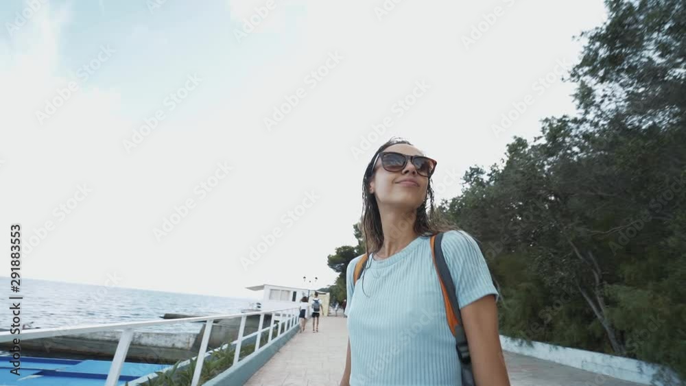 outside portrait of Beautiful young cheerful smiling woman in casual wear and small backpack standing at seaside, against a blue sea. portrait luxury resort carefree tourism destination female sexy outside portrait of Beautiful young cheerful smiling woman in casual wear and small backpack standing at seaside, against a blue sea. portrait luxury resort carefree tourism destination female sexy