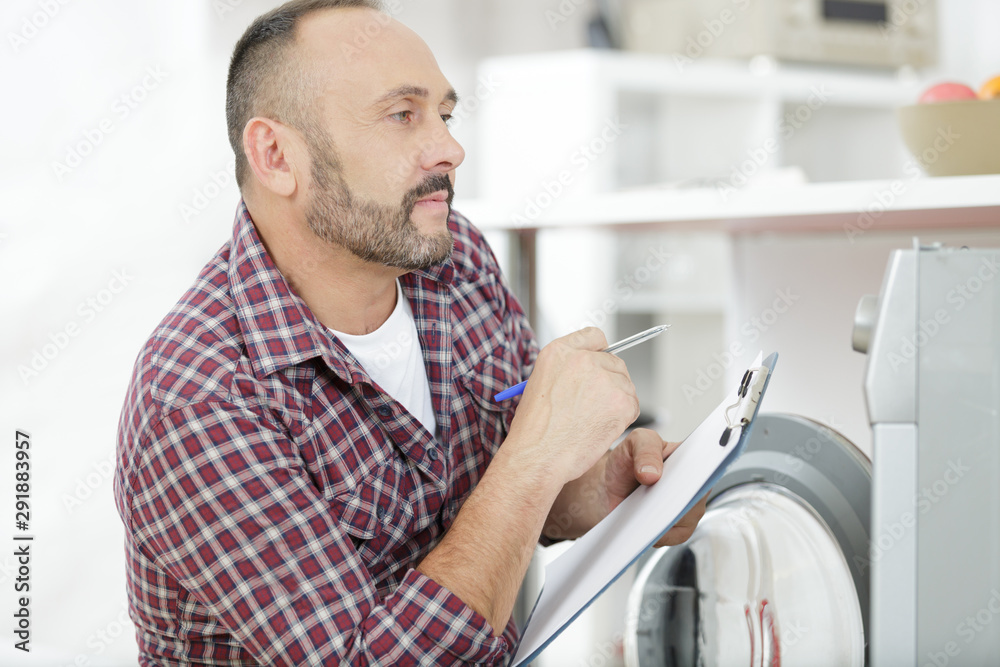 repairman examining a washing machine repairman examining a washing machine