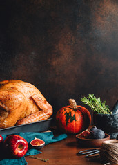 Festive table for Thanksgiving Holiday with whole roasted turkey with apple, pumpkin, figs and herbs in a mortar.