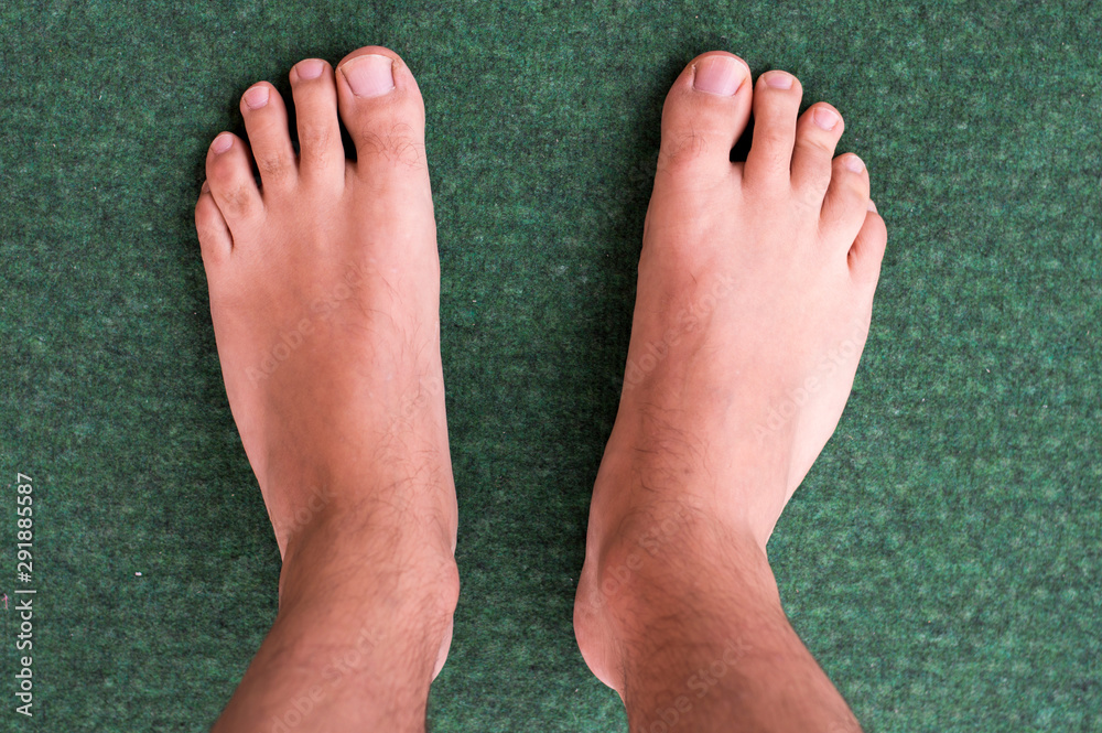 Fototapeta premium Selective focus. Male feet on green carpet.