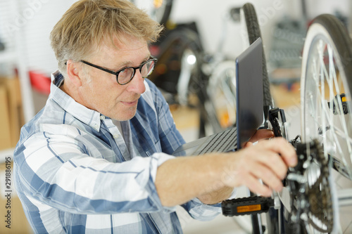 man fixing bike wheel in store