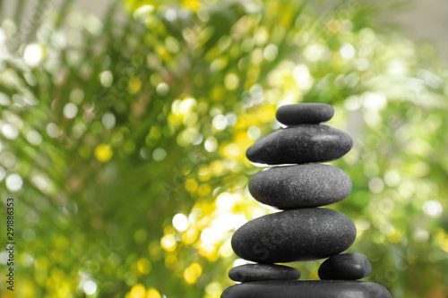 Stack of stones and blurred green leaves on background  space for text. Zen concept