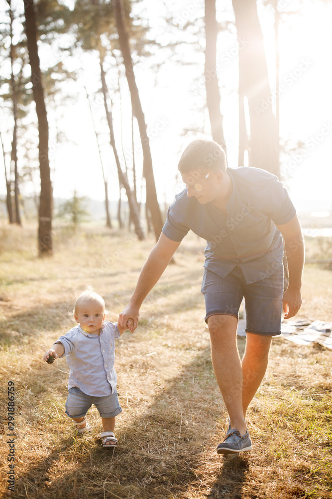 Young father walks with his cute little boy in a forest. Father's Day Young father walks with his cute little boy in a forest. Father's Day