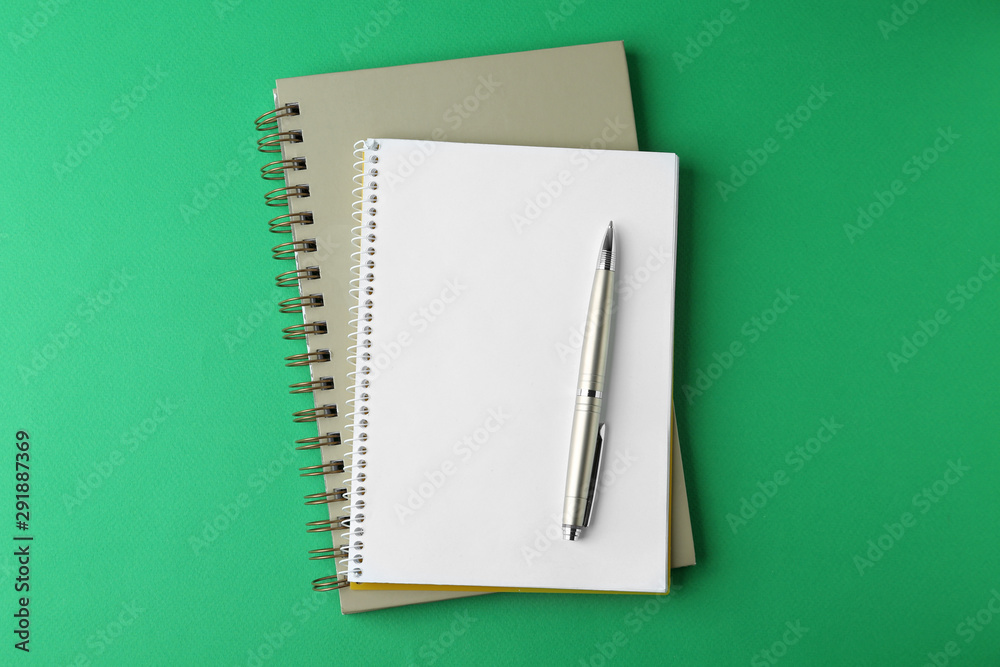 Notebooks and pen on green background, top view Notebooks and pen on green background, top view