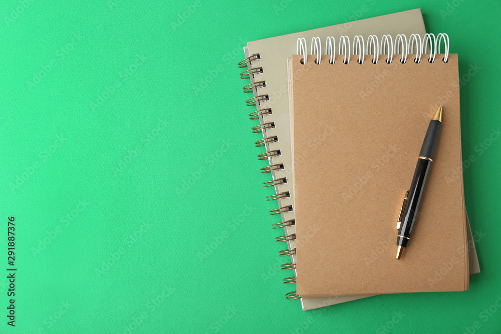 Notebooks and pen on green background, top view. Space for text Notebooks and pen on green background, top view. Space for text