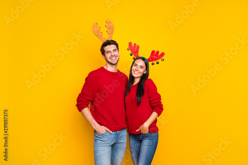 Portrait of two lovely people romantic couple hug enjoy wear elk horns mask red pullover denim jeans isolated over yellow background © deagreez