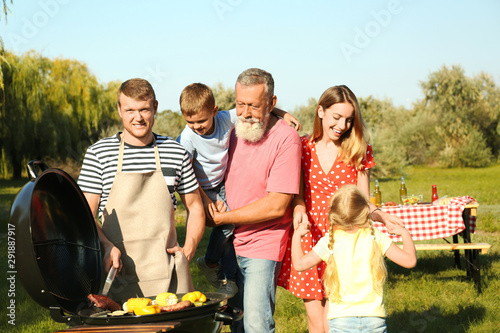 Happy family having barbecue in park on sunny day
