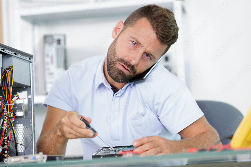man on the phone fixing a pc man on the phone fixing a pc