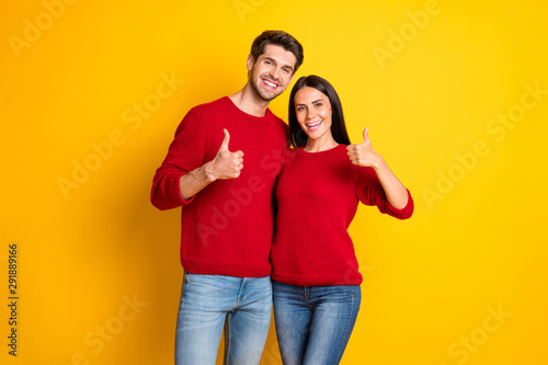Portrait of lovely spouses show thumb up recommend ads wear red jumper denim jeans isolated over yellow background