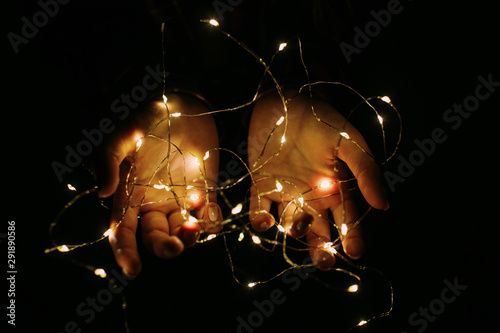 Christmas lights shining warmly closeup. Holding cozy garland in hands.