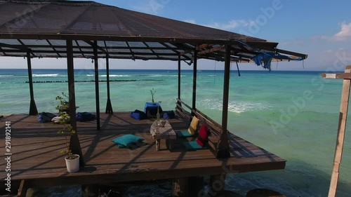 dream holiday public beach terrace, wooden pier platform with balinese seating, amazing sea view, shot from moving drone, gili trawangan, bali, indonesia