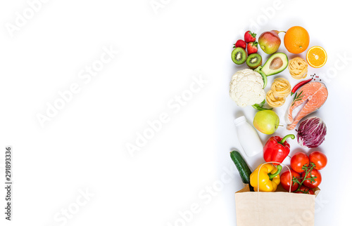 Healthy food in paper bag fruits, vegetables, milk, pasta and fish on white background. Healthy food background. Shopping food supermarket, meal and nutrition plan concept. Top view and copy space