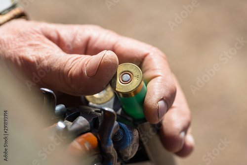 Close up of hunter loading shotgun, holds a gun and ammunition in his hand.