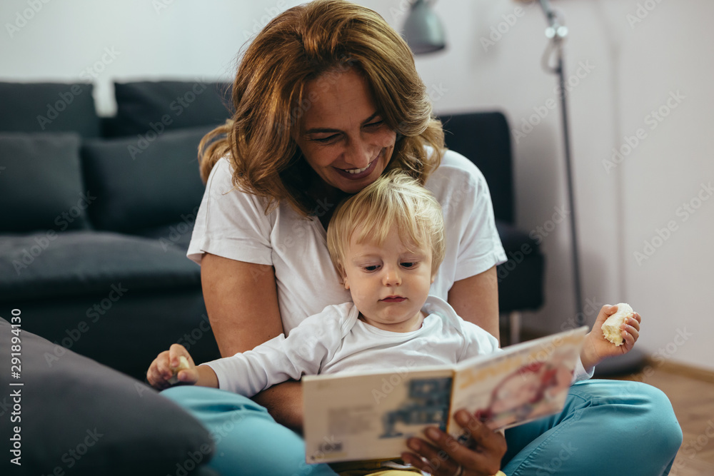 woman with her grandson reading picture book at home woman with her grandson reading picture book at home