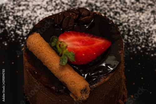 Chocolate mousse with strawberry and chocolate stick on a black dish.