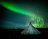 Aurora borealis (Northern Lights) over a traditional Lavvu, Senja