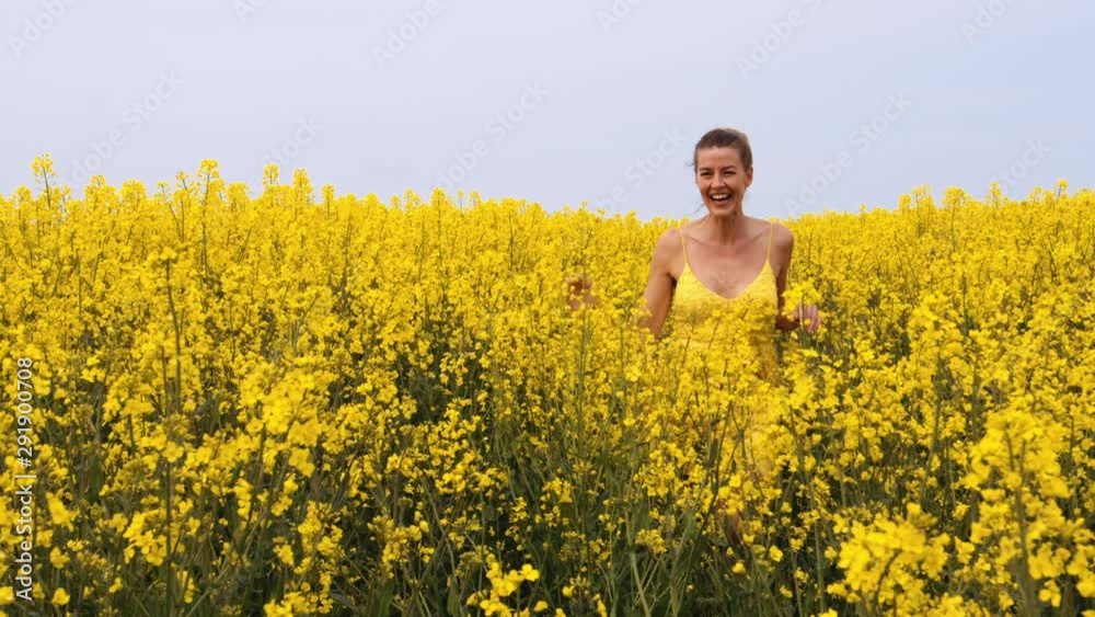 Woman Running and Swaying Her Hands Across the Field of Canola Flowers
