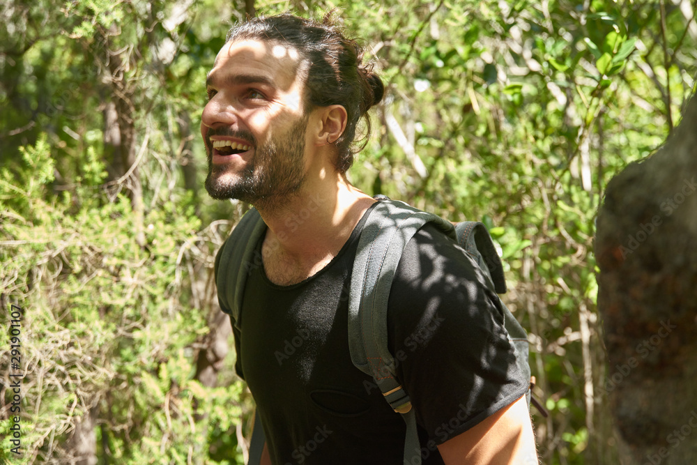 Young man smiles and looks up while walking