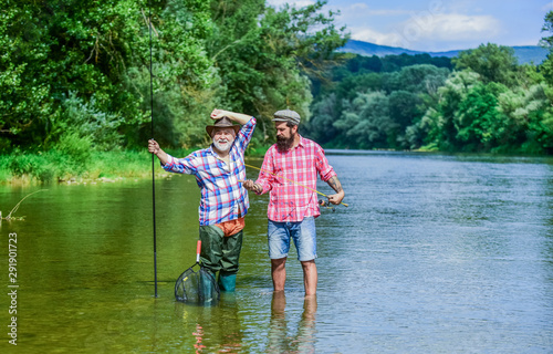 Fishing freshwater lake pond river. Mature man with friend fishing. Summer vacation. Bearded men catching fish. Family time. Activity and hobby. Happy cheerful people. Fisherman with fishing rod