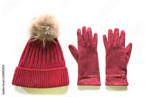Isolated cozy and warm winter flat lay. Dark red knitted hat with fur pompom and burgundy gloves on white background