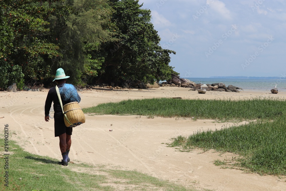Fisherman with a wicker basket and fishing net goes to the sea. Picturesque  landscape of Thailand coast Stock Photo