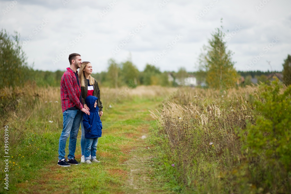 young father and mother, together with their little son, enjoy the views in the countryside on a cool evening