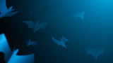 Halloween picture of blue paper bats on blank dark blue background.