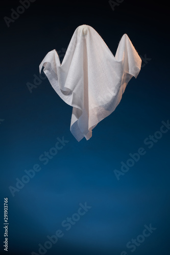 Photo of halloween ghosts made of white fabric on empty dark blue background
