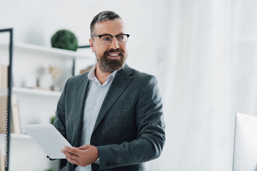 handsome businessman in formal wear and glasses using digital tablet in office