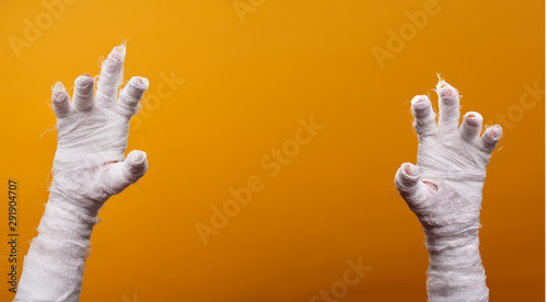 Photo of two mummy hands on empty orange background .