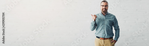 panoramic shot of handsome businessman in shirt showing thumb up and looking at camera