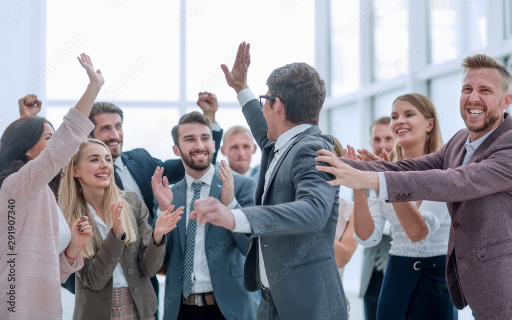 group of cheerful company employees congratulating their colleague