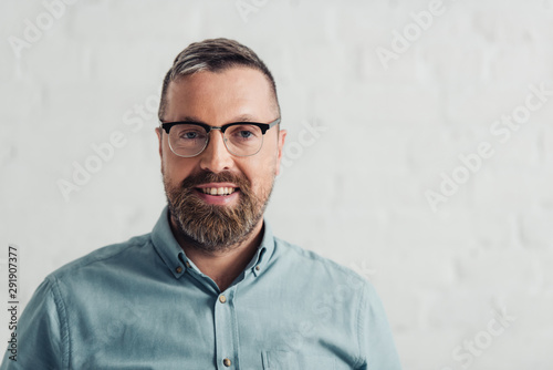 handsome businessman in shirt and glasses smiling and looking at camera