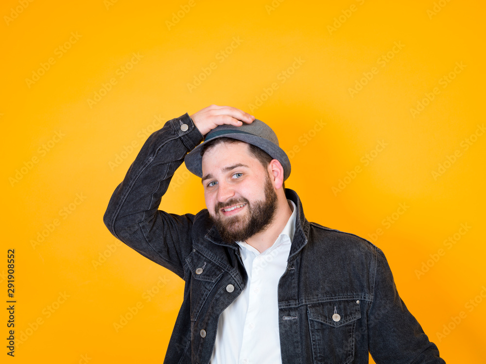cool man with hat and black beard is posing in front of yellow, orange background cool man with hat and black beard is posing in front of yellow, orange background