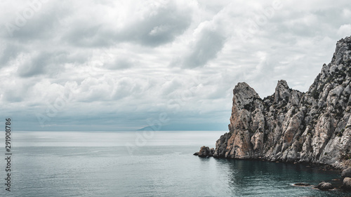 Wide angle landscape of sea and cloudy sky with cliff
