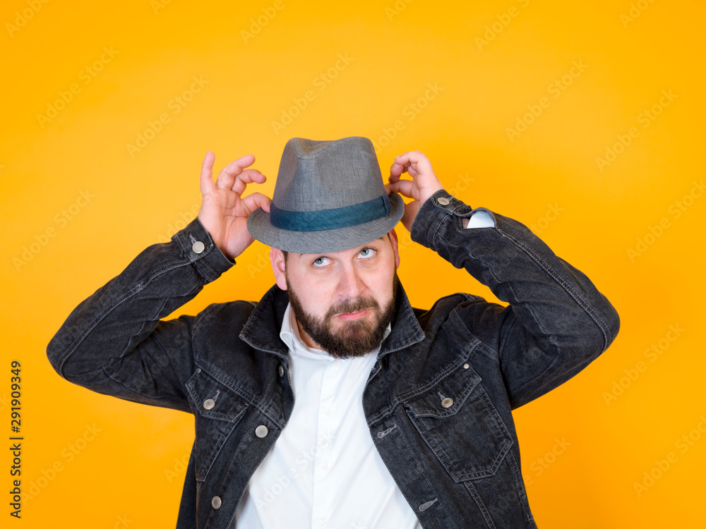 cool man with hat and black beard is posing in front of yellow, orange background cool man with hat and black beard is posing in front of yellow, orange background