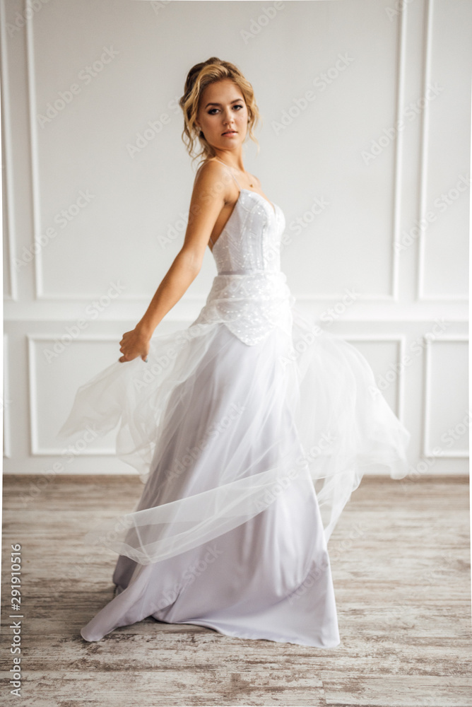 the bride in a beautiful dress is spinning in a white Studio