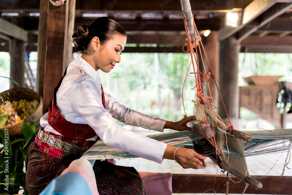 side view of Asian woman weaving silk sari on loom. female works on cotton or silk weaving with traditional hand weaving loom. Asian traditional culture. concept of life, people and Small business