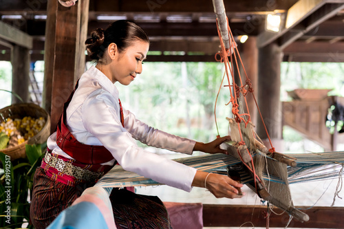 side view of Asian woman weaving silk sari on loom. female works on cotton or silk weaving with traditional hand weaving loom. Asian traditional culture. concept of life, people and Small business © Joke Phatrapong