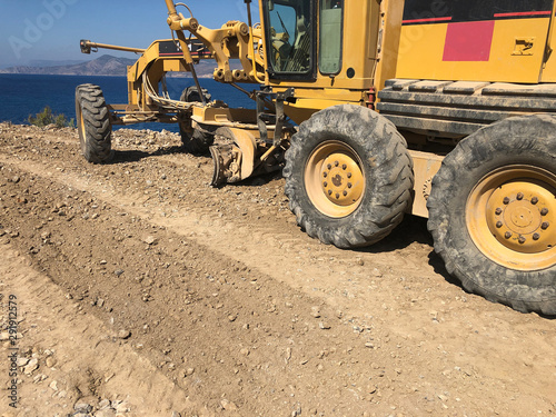 Planning of a road surface. Motor grader during road construction works. Earthmoving, excavations, digging