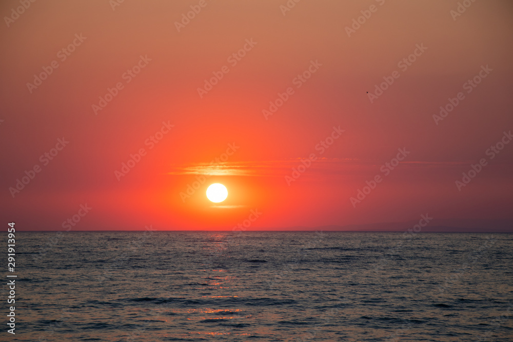 Sunset at sea during a beautiful golden hour. Landscape of the sun setting on the horizon.