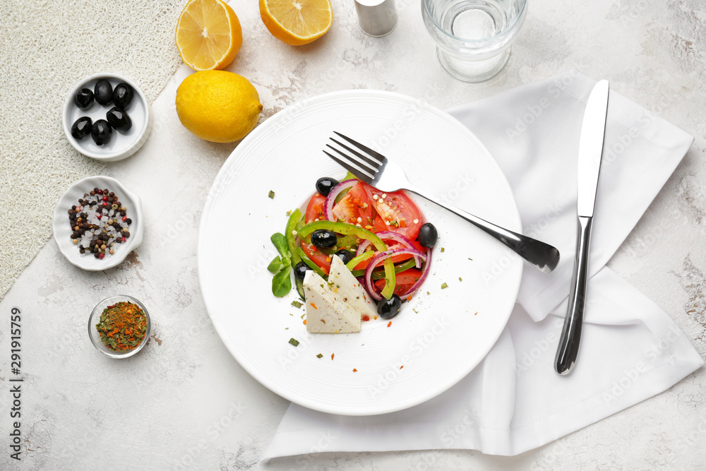 Plate with tasty Greek salad on light table Plate with tasty Greek salad on light table