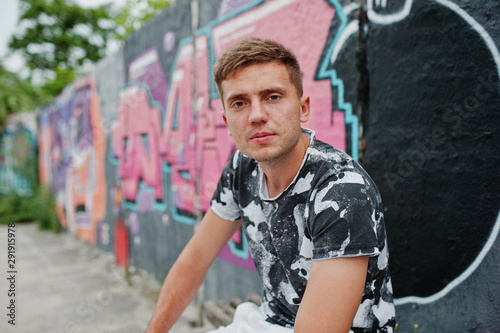 Lifestyle portrait of handsome man posing on the street of city with graffiti wall. © AS Photo Family