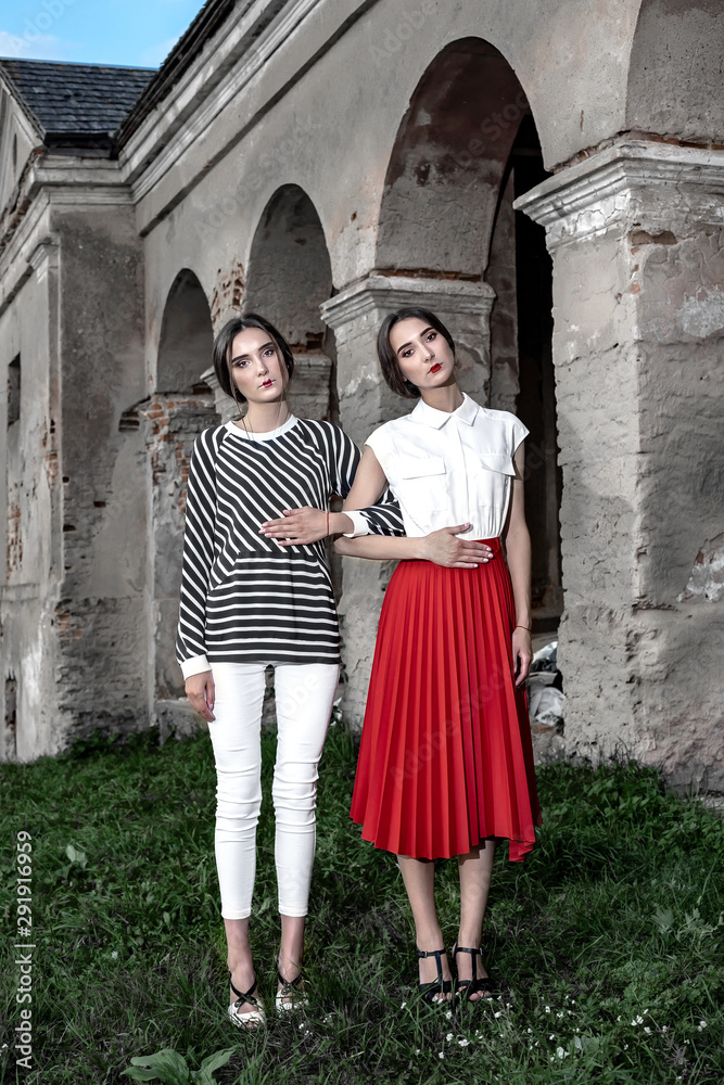 Outdoor fashion portrait of two young beautiful women wearing fashionable clothes posing on the street