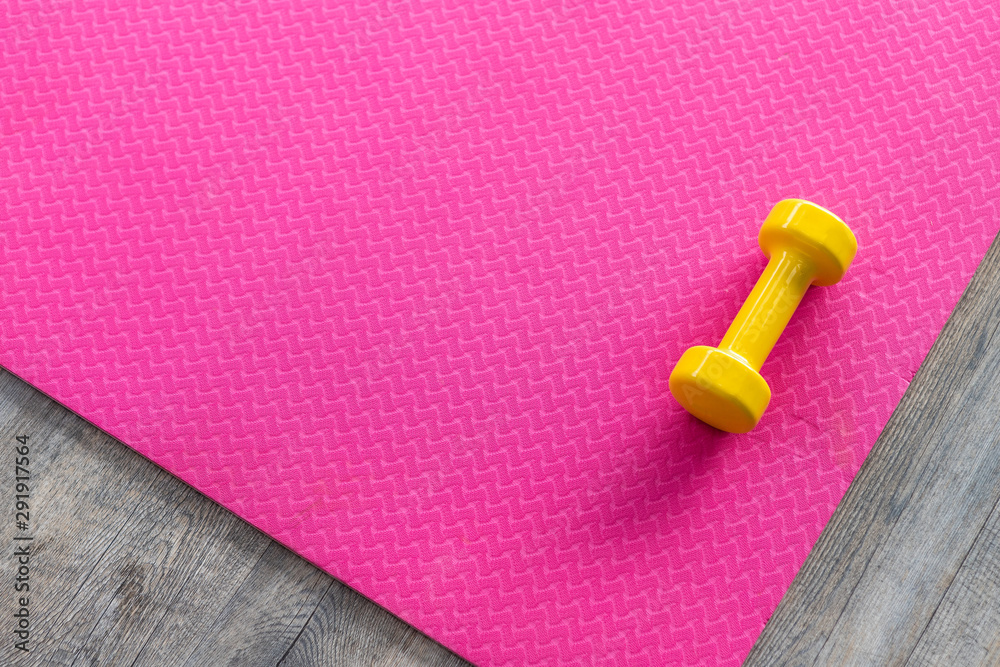 Dumbbells on an empty pink rubber floor on wooden floor background,top view with copy space health and exercise concept Dumbbells on an empty pink rubber floor on wooden floor background,top view with copy space health and exercise concept